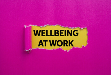 Wellbeing at work message written on ripped torn pink paper on yellow background. Conceptual wellbeing at work symbol. Copy space.