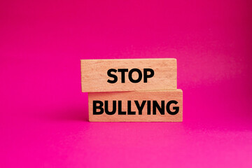 Stop bullying message written on wooden blocks on pink background. Conceptual stop bullying symbol. Copy space.