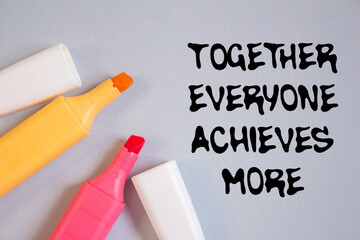 Together everyone achieves more message written on grey background with colorful marker pens....