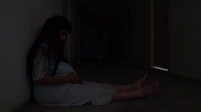 Ghost of a pregnant woman in white dress, standing alone in the dark. Traditional Asian ghost story. Horror concept with supernatural, haunted, and eerie atmosphere.