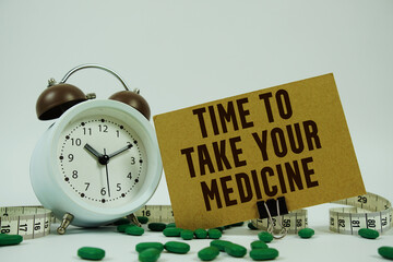 Time To Take Your Medicine text with medicine, alarm clock and measuring tape on white background