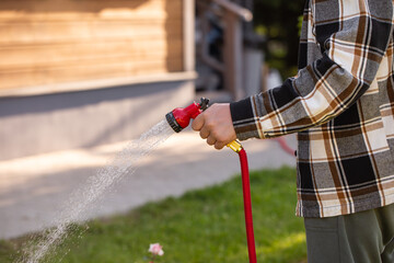 Watering garden trees, a man waters plants with a hose	