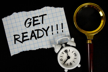 Get Ready text written on paper with magnifying glass and alarm clock
