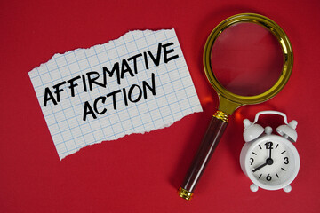 Affirmative Action text written on paper with magnifying glass and alarm clock