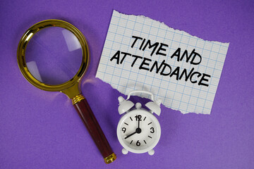 Time and Attendance text written on paper with magnifying glass and alarm clock