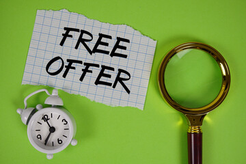 Free Offer text written on paper with magnifying glass and alarm clock