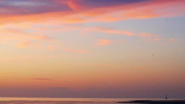 Under a radiant seaside sunset, a distant lighthouse anchors the horizon while flocks of birds soar through softly tinted skies&mdash;gentle waves ripple below, capturing peaceful motion, ambient light, and