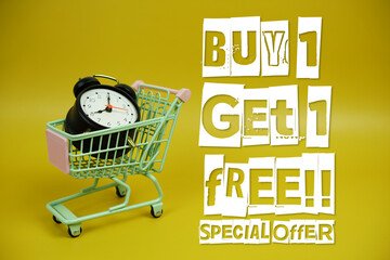 Buy 1 Get 1 Free!! Promotion and Marketing with trolley shopping cart and alarm clock on yellow...