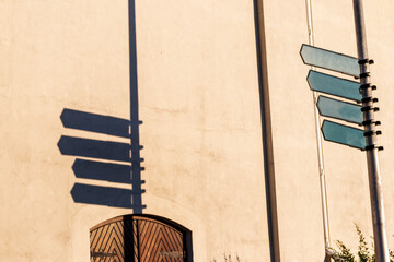 Old style direction signs casting shadow on near by wall. Concept
