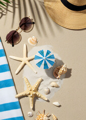 Summer flatlay with beach hat, shells and striped towel on sand