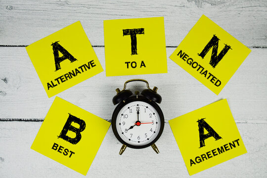 BATNA Best Alternative To A Negotiated Agreement text written on sticky note and alarm clcok flat lay on wooden background