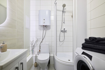 A Compact and Modern Bathroom that includes Both a Shower as well as a Washing Machine
