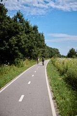 Two adults enjoy leisurely bike ride along picturesque country path surrounded by lush greenery