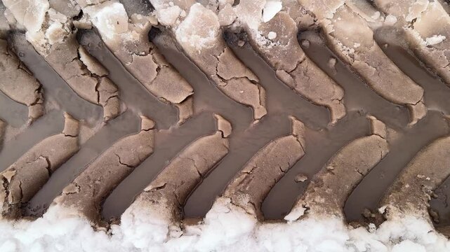 a puddle on the road, melt water flows down the tire treads in the spring