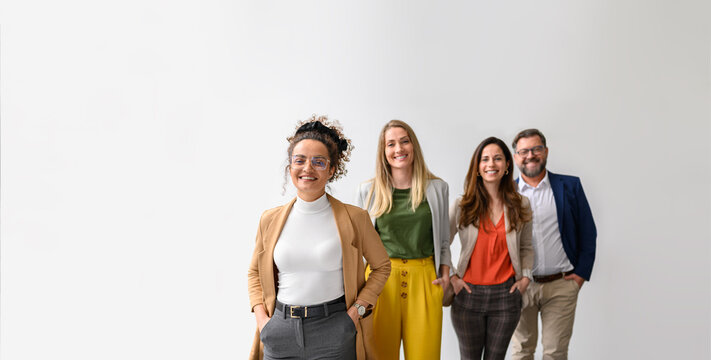 Portrait of confident business people with hands in pockets smiling and standing in a row over white background