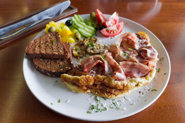 Omelette served with grilled bacon, mushrooms, fresh vegetables and bread