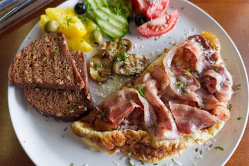 Omelette served with grilled bacon, mushrooms, fresh vegetables and bread