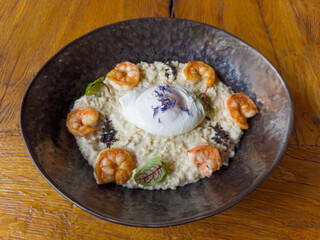 Poached egg with oatmeal and grilled prawn tails on dish