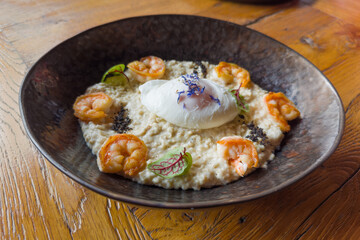Poached egg with oatmeal and grilled prawn tails on dish