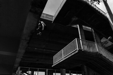 Black and white photo of a man performing a parkour trick. Extreme sports photo.
