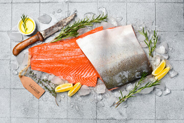 Fresh coho salmon fillet with lemon, rosemary and spices on ice. Fish cooking recipe. On a gray...
