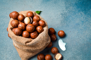 Linen bag with macadamia nuts. Set of nuts in shell in bag. On slate gray background.