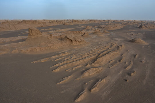 Aerial view of the mesmerizing yardangs casting long shadows under the vast sky, creating a stunning contrast between light and shadow, Kerman, Kerman Province, Iran.