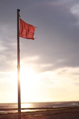 Red flag is flying on a pole in the ocean