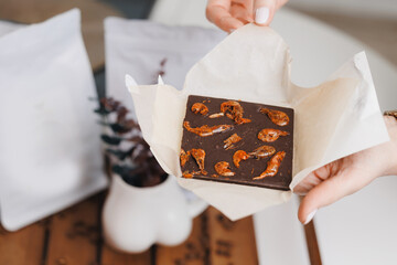 Hands holding unique chocolate bar with edible insects shrimps on parchment paper