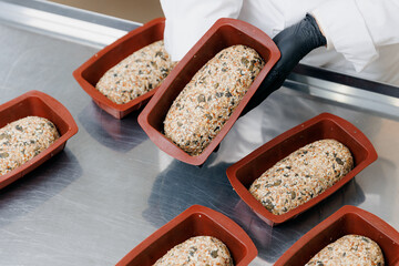 Baker prepares free gluten multigrain bread with seeds, shapes it for baking in oven. Bakery eco...
