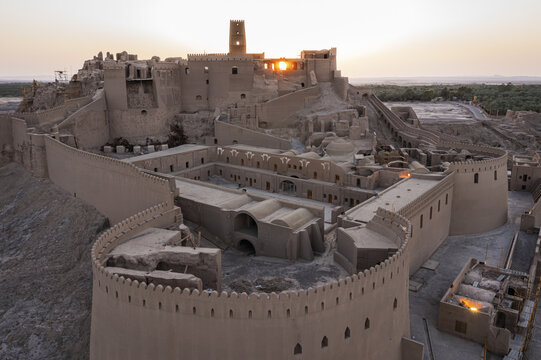 Aerial view of the ancient Arg-e Bam citadel glows in warm light against the desert landscape, a testament to history and resilience, Bam, Kerman Province, Iran.