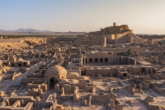 Aerial view of ancient ruins and crumbling structures bask in the warm glow of the setting sun, evoking a sense of timeless history, Bam, Kerman Province, Iran.