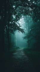 Obraz premium Misty forest path with deep blue fog and silhouetted trees creating a moody, mysterious atmosphere.