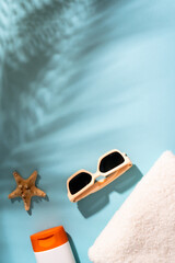 Sunglasses, sunscreen and sea shell with sunny shadows.