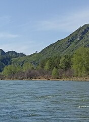 Picturesque mountain river landscape with lush vegetation and clear blue sky above scenery