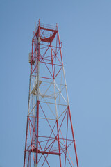 unfinished red and white radio tower against a clear blue sky, radio broadcast