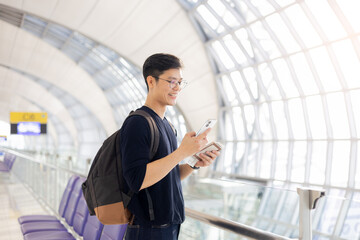 close up young asian man smile and looking while holding passport ,ticket and smartphone in airport...