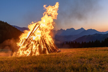 Solstice bonfire with sunset in the background in the Alps