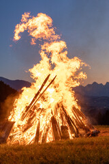Solstice bonfire with sunset in the background in the Alps
