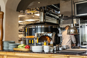 A chef in restaurant kitchen focused on his work, surrounded by cooking equipment, utensils and...