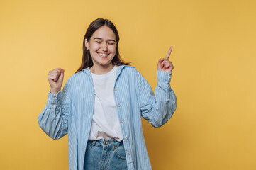 joyful woman dances with excitement, expressing happiness  on vibrant yellow background