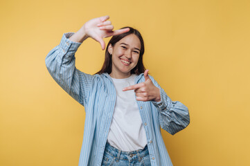 young woman playfully framing a scene with her hands, full of creativity and imagination on vibrant...
