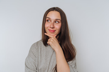 thoughtful young woman with long hair rests her chin on her hand, signifying deep contemplation and...