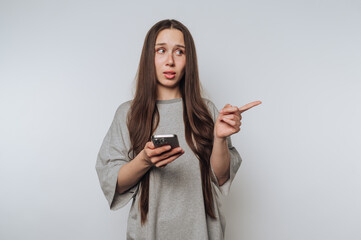 thoughtful woman points at her smartphone with an inquisitive look, embodying curiosity and...