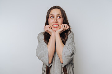 young woman expresses fear through her body language on white background