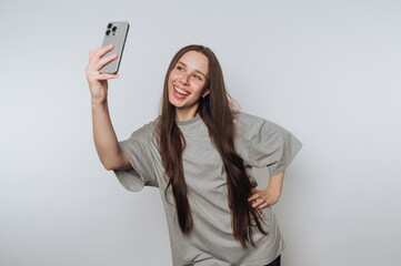 playful woman enjoys sharing a joyful moment with her smartphone, taking selfie on white background