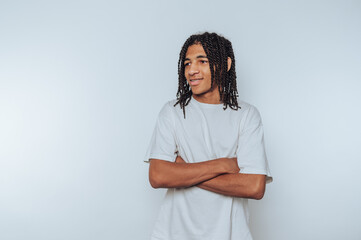 confident young man stands with arms crossed, wearing a plain white t-shirt and displaying a...