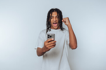 young man displays excitement while looking at his smartphone, showcasing a joyful moment of...