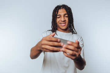 young man displays a big smile while engaged with his smartphone, portraying a moment of enjoyment...