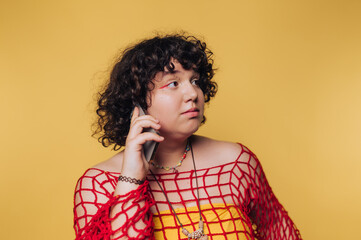 young person looks thoughtfully to the side, holding a phone while making a curious gesture on yellow background